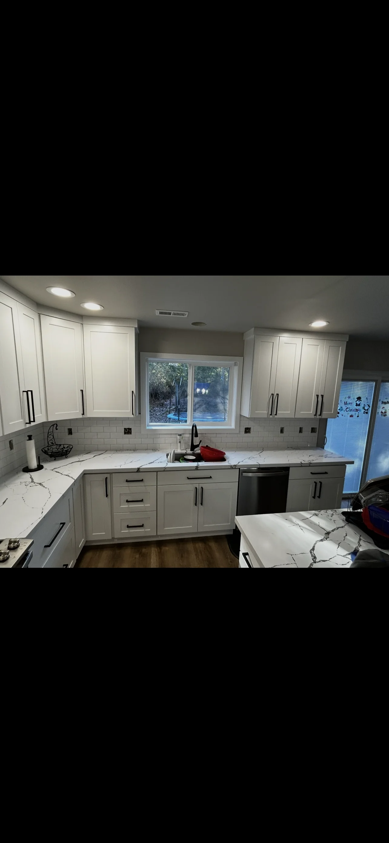 Modern kitchen with white cabinetry, marble countertops, subway tile backsplash, and stainless steel appliances