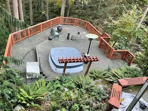 Aerial view of curved composite deck with built-in seating and wood railings surrounded by forest