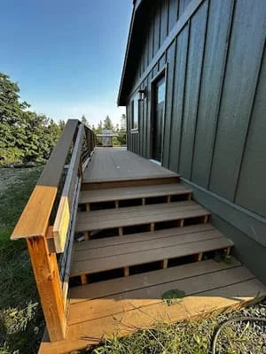 Multi-level composite deck with wooden handrails and stairs leading from home to yard